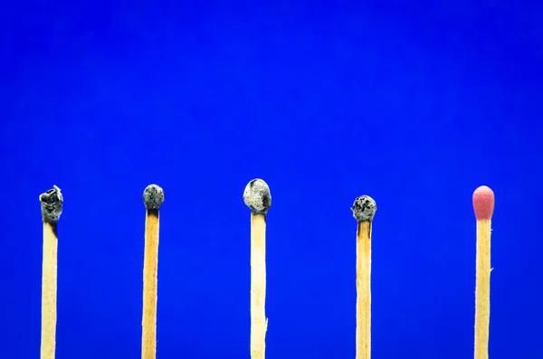 Burned match setting on blue background for ideas and inspiratio — Stock Photo, Image