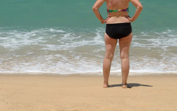 Alte Frau steht am Strand — Stockfoto