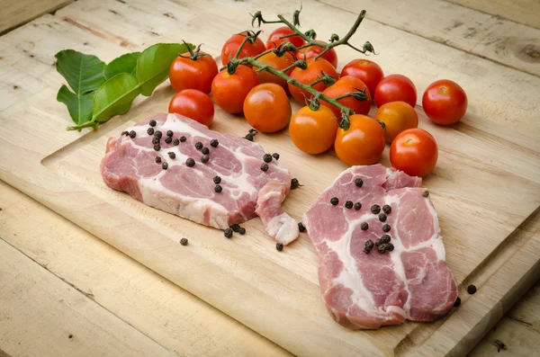 Carne de porco e tomate vermelho na placa de cozinha — Fotografia de Stock