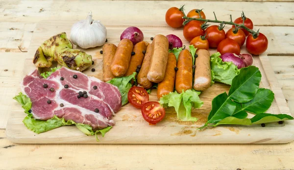 Salsichas de carne fresca e legumes na placa de cozinha — Fotografia de Stock