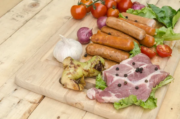 Fresh meat sausages  and vegetables on kitchen board — Stock Photo, Image