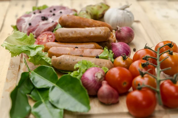 Fresh meat sausages  and vegetables on kitchen board — Stock Photo, Image