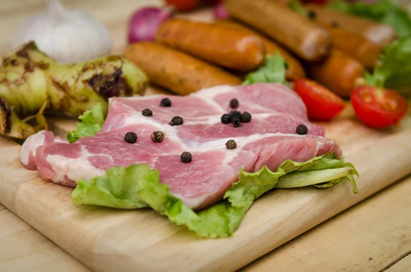 Salsichas de carne fresca e legumes na placa de cozinha — Fotografia de Stock