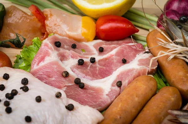 Свежие мясные сосиски и овощи на кухонном столе — стоковое фото