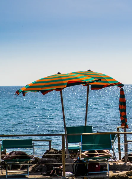 Kleurrijke paraplu op een rots strand — Stockfoto