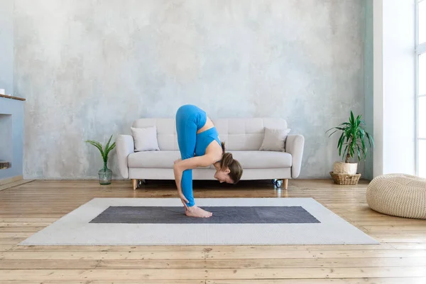 Athletic woman doing sports at home doing yoga stretching