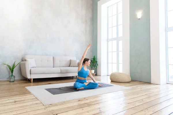 Woman doing sports at home practicing yoga stretching in lotus position