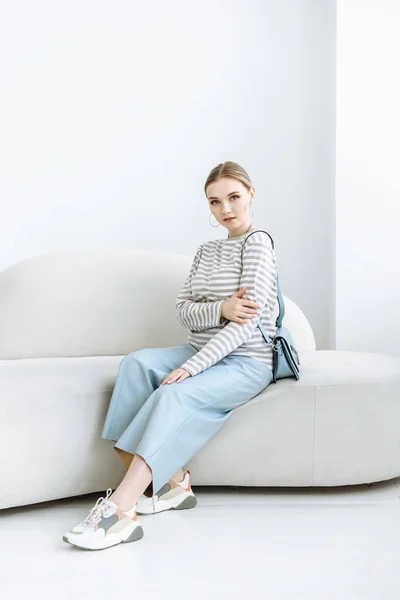 Woman model sitting on sofa in white room