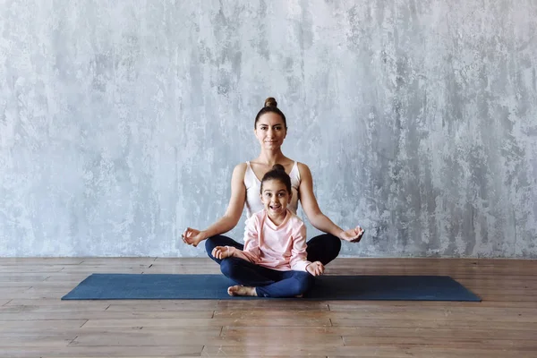 mom and daughter practice yoga on the carpet indoors