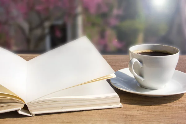 Coffee cup with open book over spring garden