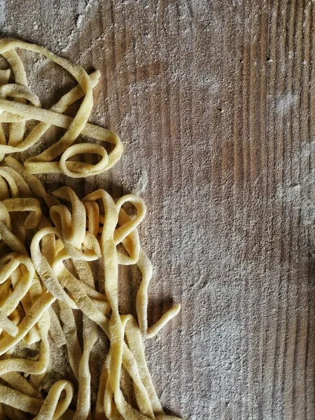 Wooden table with pasta and flour