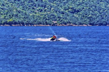 Bir adam güneşli yaz gününde açık denizde deniz boku sürüyor..