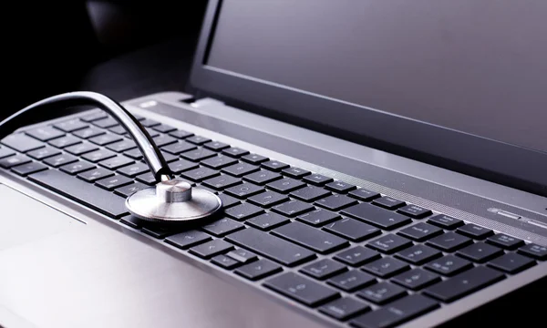 Estetoscópio que descansa em um teclado de computador - conceito para medicina online ou suporte de TI — Fotografia de Stock