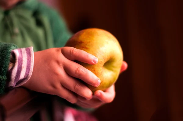 Kind hält einen Apfel in der Hand — Stockbild Kind hält einen Apfel in der Hand — Stockfoto