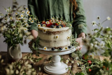 Böğürtlen ve çiçeklerle süslenmiş güzel bir yaz pastası yeşillikler arasında duruyor..