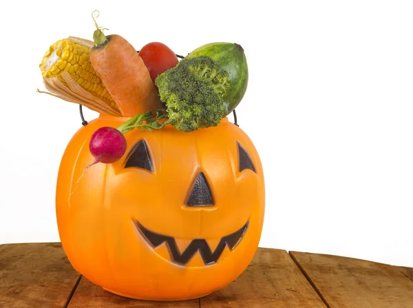 Halloween Healthy plastic Pumpkin full of Vegetables on wooden table on white background — Stock Photo, Image