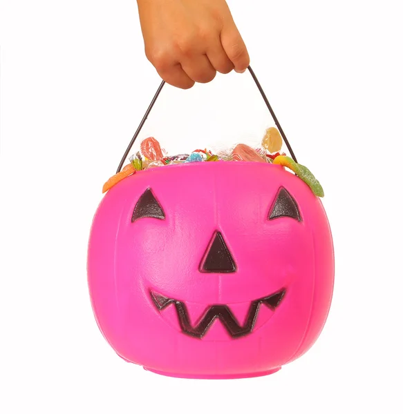 Kid holding a pink plastic pumpkin filled with candy — Stock Photo, Image