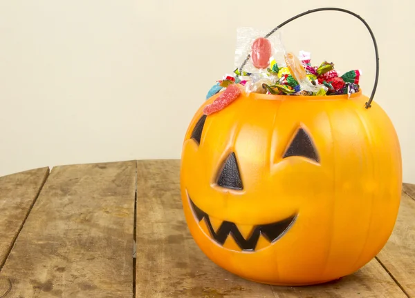 Halloweengresskar av plast fylt med sukkertøy på trebord – stockfoto