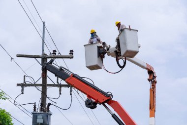 Elektrikçi yüksek voltaj iletim hatlarını korumak için kova vagon üzerinde çalışıyor..