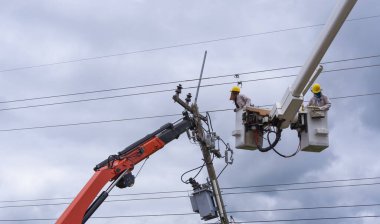 Elektrikçi yüksek voltaj iletim hatlarını korumak için kova vagon üzerinde çalışıyor..