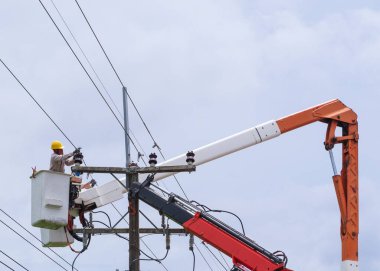 Elektrikçi yüksek voltaj iletim hatlarını korumak için kova vagon üzerinde çalışıyor..