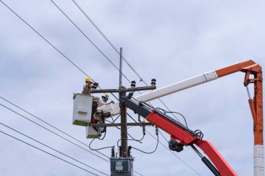 Elektrikçi yüksek voltaj iletim hatlarını korumak için kova vagon üzerinde çalışıyor..