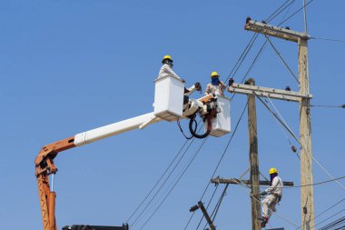 Elektrikçiler yüksek gerilim sistemine ekipman yüklüyorlar.