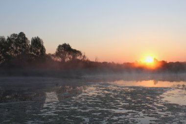 Göl üzerinde yükselen güneş. Sis. İhale renkleri