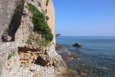 Eski kale duvarı ve deniz. Güneşli bir gün ve açık mavi bir gökyüzü. Seyahat ve maceralar. Oyun ortamı tasarımı için dokular