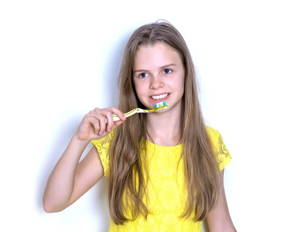 Young girl in a yellow dress brushing her teeth — Stock Photo, Image