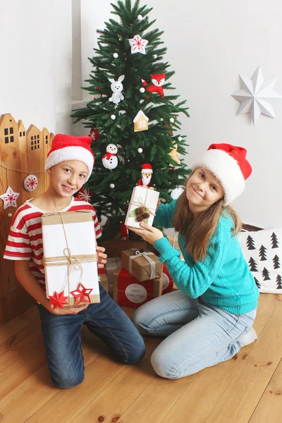Smiling boy and girl with presents near Christmas tree — Stock Photo, Image