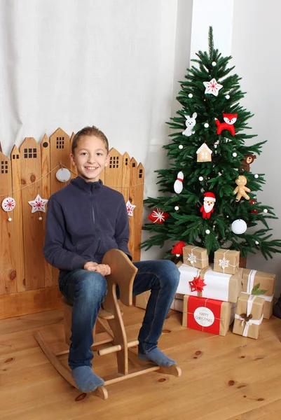 Happy boy on the wooden horse near Christmas tree — Stock Photo, Image