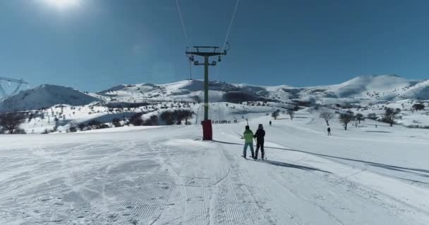 Вид с воздуха на двух профессиональных лыжников, поднимающихся на вершину горы на кресельном подъемнике. — стоковое видео