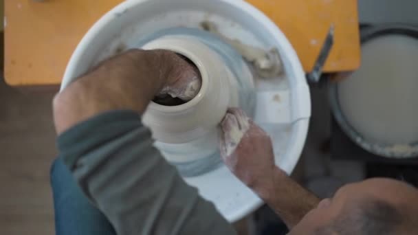 Roue de potiers, mains forme pot d'argile sur la roue de potiers, maître expérimenté faisant un pot sur une roue de poterie, mains travaillant sur la roue de poterie production traditionnelle et manuelle de poterie — Video