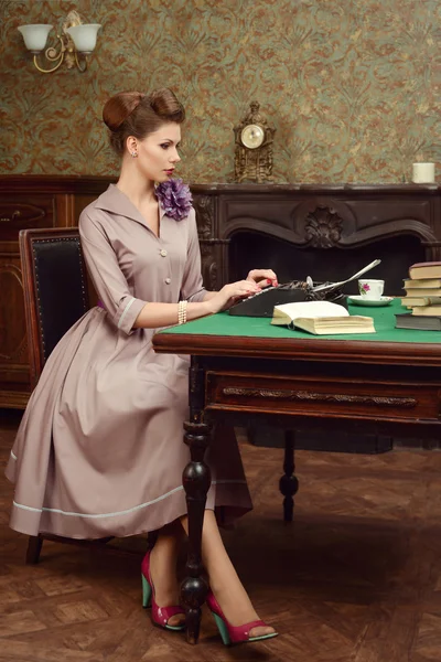 Pin Up bella giovane donna in interni vintage leggere un libro e stampe su una vecchia macchina da scrivere — Foto Stock
