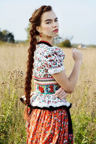 Jonge boer vrouw, gekleed in Hongaarse nationale kostuum, die zich voordeed op aard achtergrond — Stockfoto