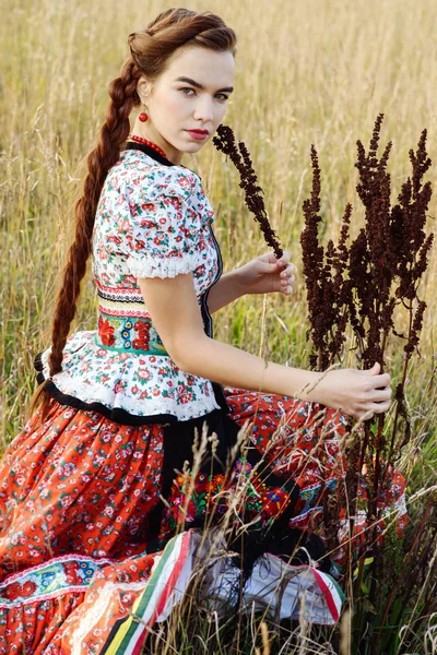 Jonge boer vrouw, gekleed in Hongaarse nationale kostuum, die zich voordeed op aard achtergrond — Stockfoto