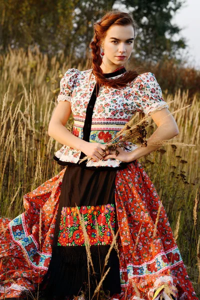 Young peasant woman, dressed in Hungarian national costume, posing over nature background — Stock Photo, Image