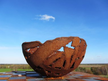 Rusted bowl with blue sky as background clipart