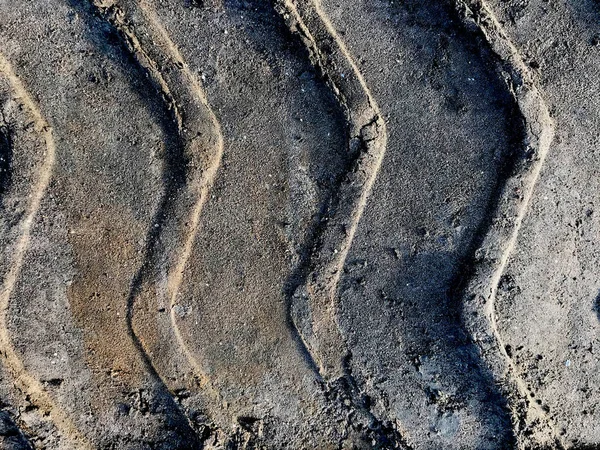 Tinted photo of footprints in the sand, earth, dirt from tire treads, car wheels. Industrial, construction, heavy machinery, dump trucks, trucks, tractors, loaders
