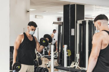 Çocuk aynanın önünde egzersiz yaparken maske takıyor.