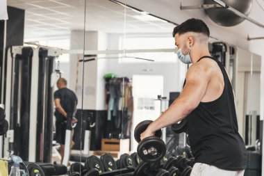 Çocuk aynanın önünde egzersiz yaparken maske takıyor.