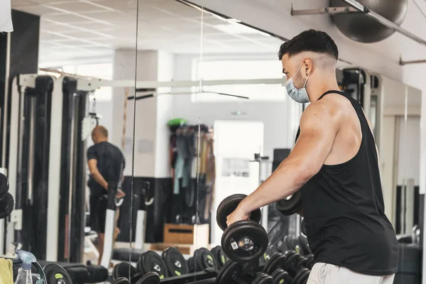 Çocuk aynanın önünde egzersiz yaparken maske takıyor.