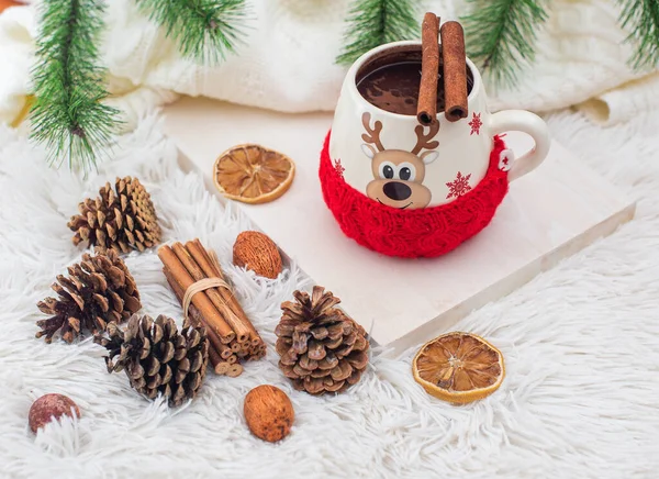Christmas background. cup of hot cocoa whit cinnamon. dry fruits. pine cone and green branch. white fur texture.
