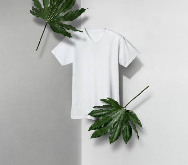 Beyaz ve gri arkaplan üzerinde yaprakları ve kısa kolları olan v şeklinde boyunlu beyaz tişört