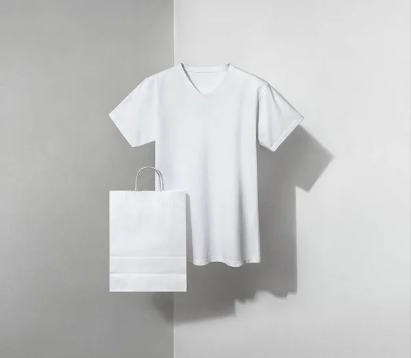 white v-neck t-shirt and paper bag on a white and grey background