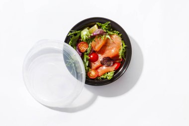 Beyaz arka planda somon salatası ve domatesli paket.
