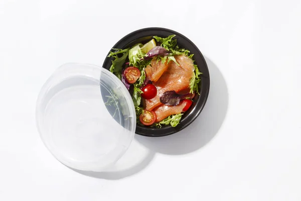 Beyaz arka planda somon salatası ve domatesli paket.