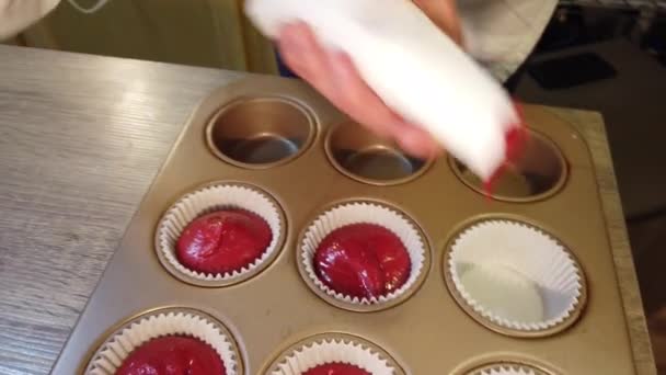 Squeezing cupcake dough into cupcake holders in a baking tray — Stock Video