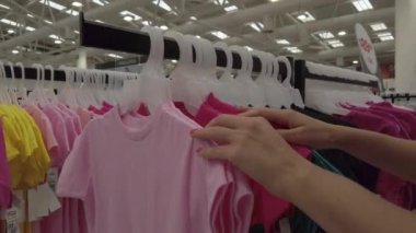 Kız dükkandan çocuk tişörtü seçiyor.